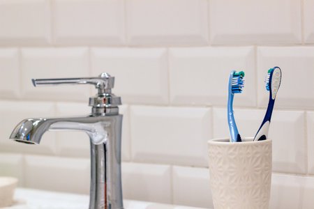 toothbrush and toothpaste in a glass on the background of the bathroomの写真素材