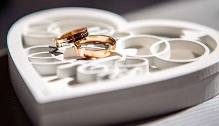 Beautiful wedding rings lie on a wooden white decorative boxの写真素材