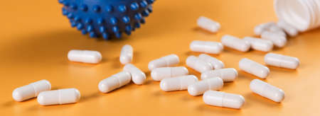 Pharmaceutical medicine pills, tablets or capsules and corona virus covid-19 cell symbol on yellow background.の写真素材