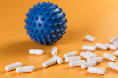 Pharmaceutical medicine pills, tablets or capsules and corona virus covid-19 cell symbol on yellow background.の写真素材