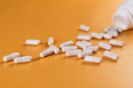Pharmaceutical medicine white pills, tablets or capsules on yellowの写真素材