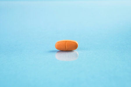Macro view of orange colored medical pill or capsule on blue background.の写真素材