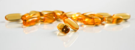Two capsules Omega 3 isolated on white background and many other of capsules on blurred background. Health care conceptの写真素材