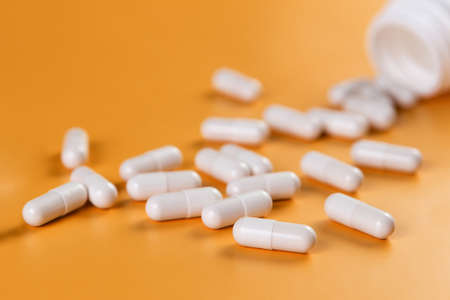 Pharmaceutical medicine white pills, tablets or capsules on yellow background. Health care concept.の写真素材