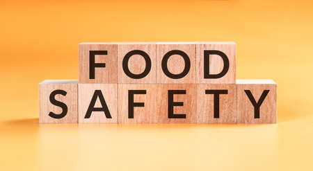 Food safety word written on wood block on yellow background.の写真素材