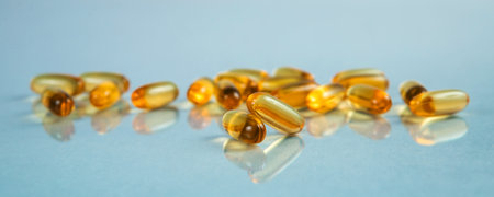 Two capsules Omega 3 on blue background and many other of capsules. Selective focus.の写真素材