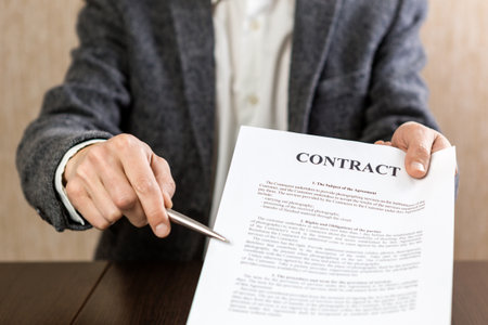 Man reading contract documents at the desk in the office. Warm sunlight.