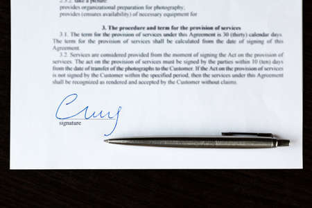 Closeup of signature and silver ballpoint pen with on contract.