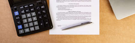 Flat lay of contract with laptop, ballpoint pen and calculator on the table.