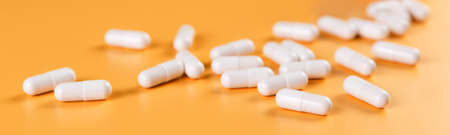Pharmaceutical medicine white capsules on yellow background.の写真素材