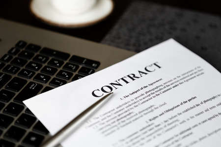 Laptop computer, contract, planner and pen on wooden table in office.の写真素材