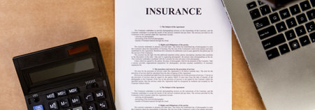 Insurance policy with laptop and calculator on the table.の写真素材