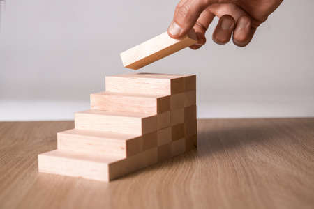 Male hand stacking wooden blocks. Business development and growth concept.の写真素材