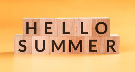 Hello Summer word written on wooden block on yellow background.の写真素材