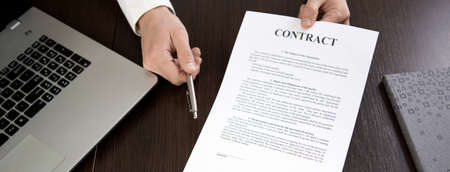 Businessman handing over a contract for signature offering a ballpoint pen in his handの写真素材
