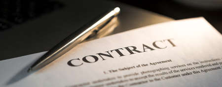 Pen for signing the contract. The ballpoint pen and contract are on the laptop.の写真素材