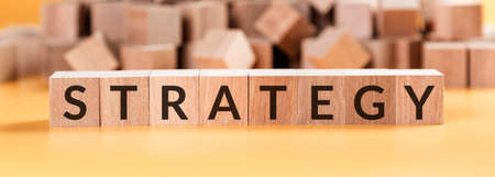 Strategy word on wooden cubes on yellow background, sucess in business concept.の写真素材