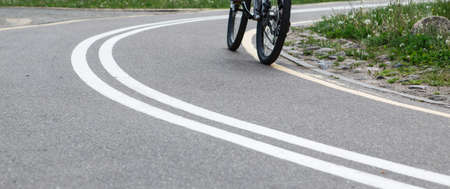 Woman riding a bike on bike path with markings in summer park.の写真素材