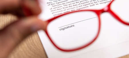 Red glasses in hand and empty place for signature of the Contract.