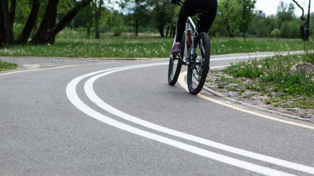 Woman riding a bike on bike path with markings in spring park.の写真素材