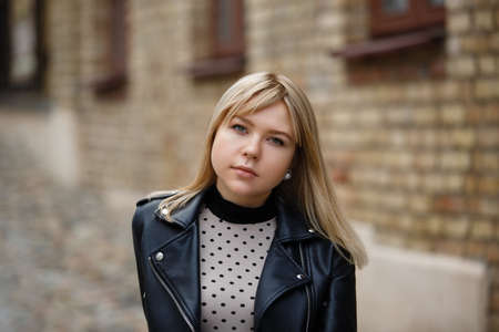 Outdoors lifestyle portrait of happy stunning blonde girl. Walking to the city street.