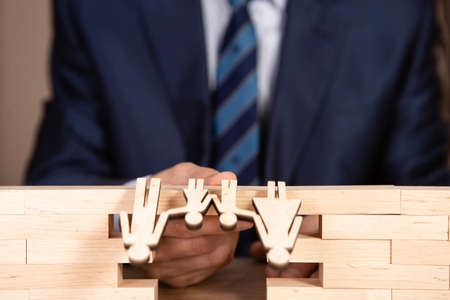 A man in a suit holds a symbolic bridge from which a family falls. Concept of life insurance.