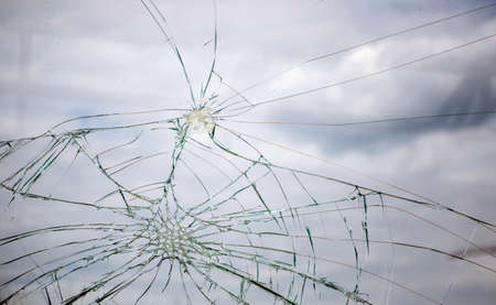 Broken Glass with Blue Sky and Clouds in Background. Cracked glass.の写真素材