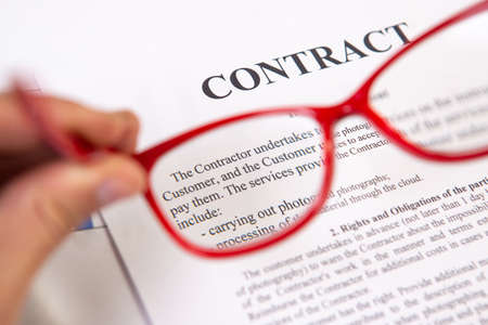Close up of contract with red reading glasses in hand. Lawyer conceptの写真素材
