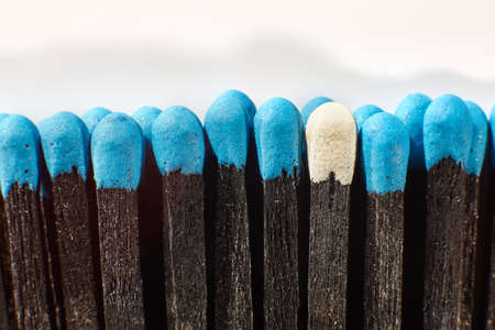 Black wooden matches with bright blue heads and one match with white head. Matchsticks without box close-up. Top view.の写真素材