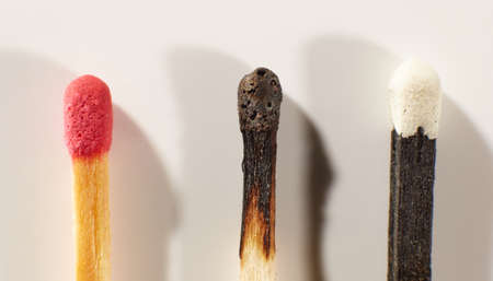 Wooden matche with red head, black wooden matche with white head and burnt match on a light gray background close-up. Matchsticks without box.の写真素材