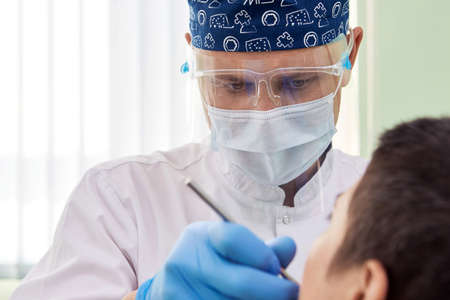 Male dentist curing patient's teeth. Stomatologist working with professional equipment in clinic office. Close-up shot.の写真素材