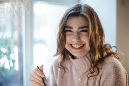 Portrait of young smiling woman looking at camera. Happy girl sitting in cafe.の写真素材