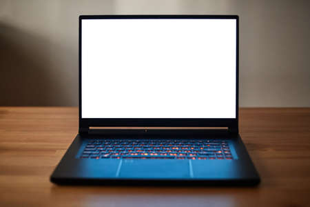 Laptop or notebook with blank screen on wood table. Keyboard monitor light.