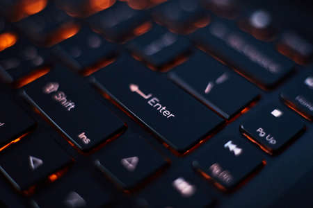 Close-up of a laptop keyboard with orange backlight. Focus on some keys.の写真素材