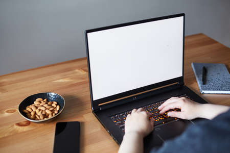 View of woman hands working on laptop with blank white screen standing on the wooden office desk. Clipping path.の写真素材