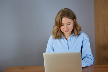 Close up portrait of a beautiful young woman looking at laptop screen. Work at home.の写真素材