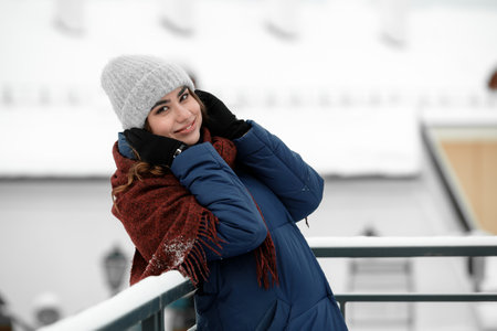 Portrait of a young happy woman enjoying winter wearing scarf and cap. Smiling girl in a colorful shawl looking at camera.の写真素材