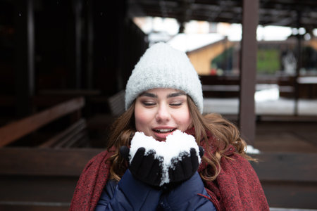 Closeup portrait of a young happy woman enjoying winter wearing scarf and knitted hat. Smiling girl in a colorful shawl looking at camera.の写真素材
