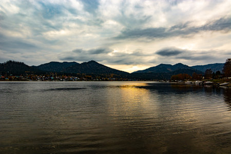 Beautiful sunset over lake in the mountains. Coastline with houses and boats.の写真素材