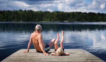 Grandfather and Grandson sitting on a footbridgeの写真素材