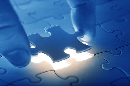 Hands placing last piece of a Puzzleの写真素材