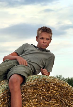 13 years old boy on a  Bale of Hay in Field in Summerの写真素材