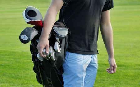 Male golfer carrying clubs, close-upの写真素材