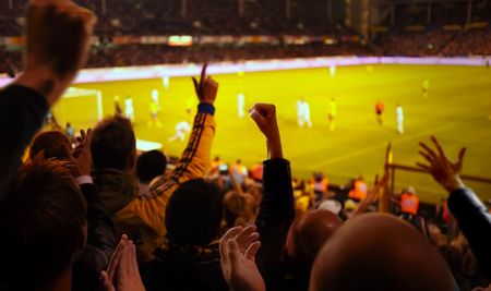 Fans excited at a football game, selective focus on fans with hands raisedの写真素材