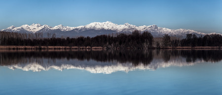 the snowcapped Alps reflected in the lake of Candiaの写真素材