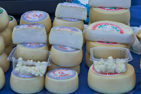 Display of traditional cheese wheels and cheese cubes in plastic containers at a local market. A delicious showcase of artisanal dairy products.の写真素材