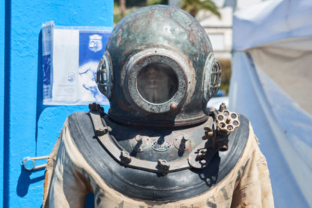 A vintage diving suit stands prominently at a coastal exhibition, surrounded by vibrant marine artifacts. The suit exemplifies early underwater exploration during clear skies.の写真素材