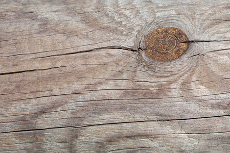 A close-up of aged, light brown wooden planks featuring prominent grain patterns, natural cracks, and a distinct, rustic knot, perfect for backgrounds or organic themes.の写真素材
