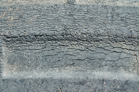 A detailed close-up of an aged and weathered rubber tire surface, displaying intricate patterns of fine cracks and wear, ideal for backgrounds or industrial themes.の写真素材