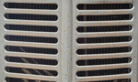 A close-up of a weathered, light-colored vehicle grille featuring horizontal slats and a fine mesh screen underneath, ideal for industrial, automotive, or grunge backgrounds.の写真素材